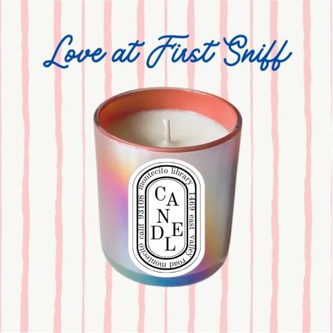 An iridescent candle with the Montecito Library address against a pink striped background.
