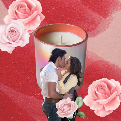 Couple kiss surrounded by roses, a candle sits in the background